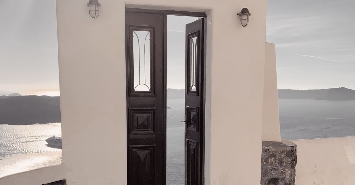 A classic Santorini doorway opens to reveal a stunning sea view, capturing Greece's tranquil beauty.