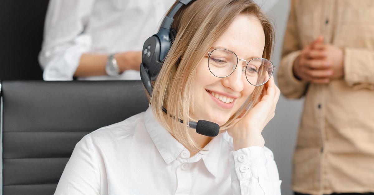 A cheerful woman working at a call center, wearing a headset and glasses, providing excellent customer support.
