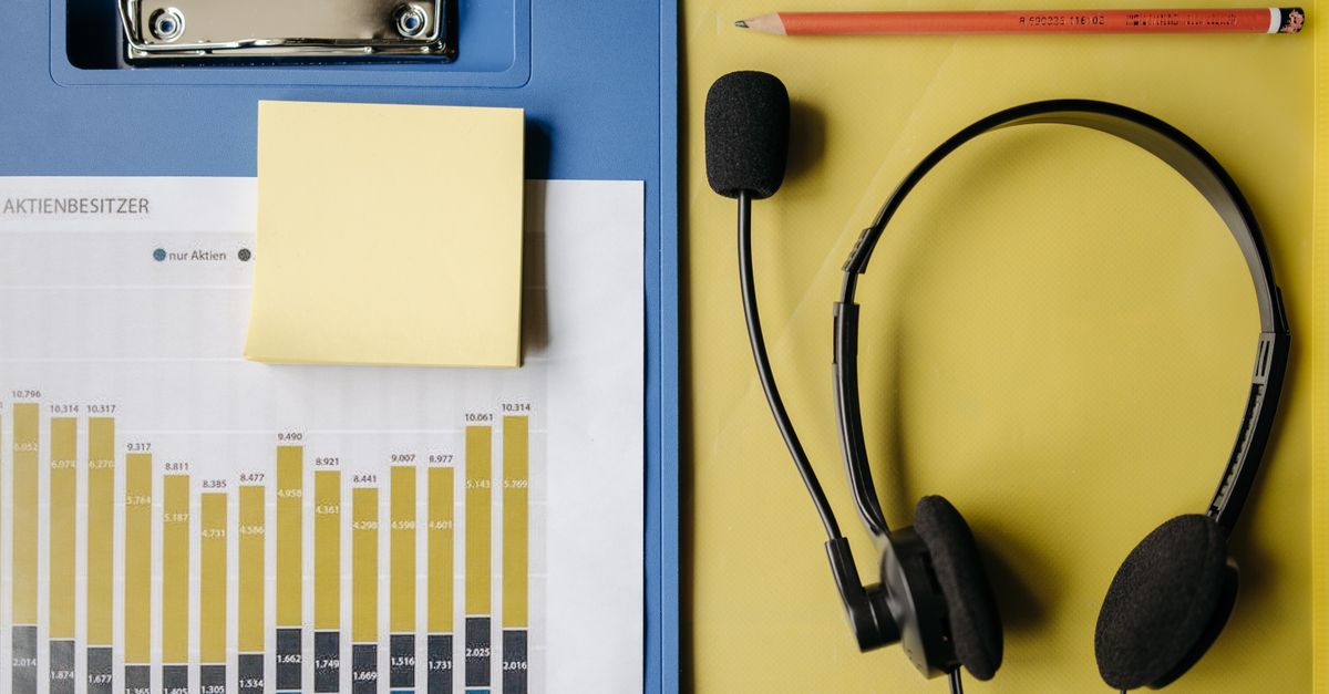Flat lay of office items including a graph, headset, and stationery on a desk.