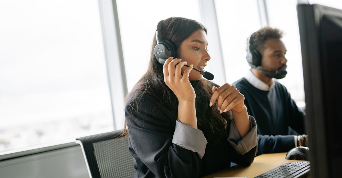 Customer service agents using headsets and computers in a modern office environment.