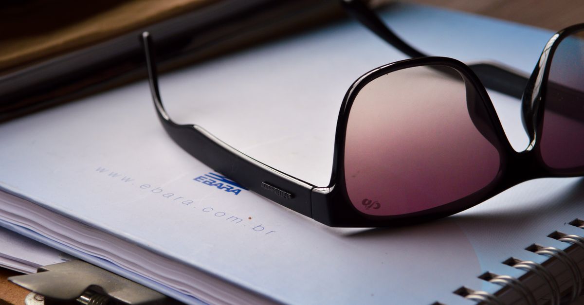 Close-up of sunglasses on a notebook with a clipboard, ideal for office or lifestyle topics.