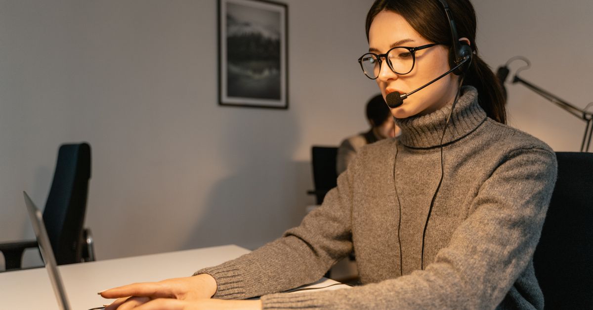 Woman in a call center providing customer support with a headset and laptop.
