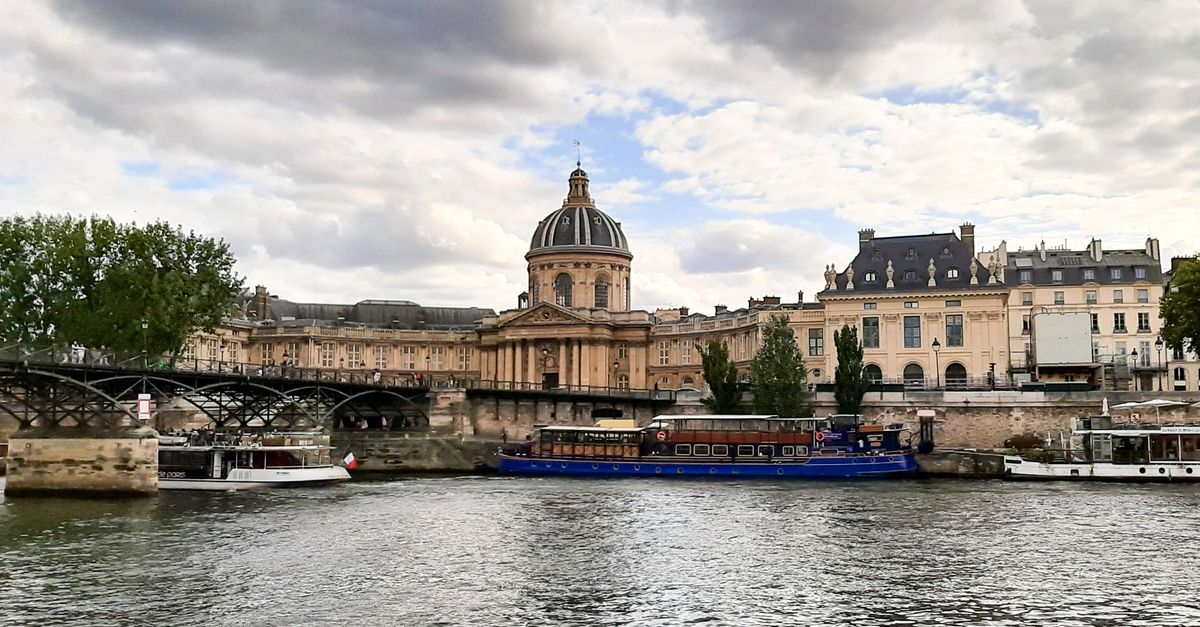 Scenic view of iconic Paris architecture along the Seine River on a cloudy day.