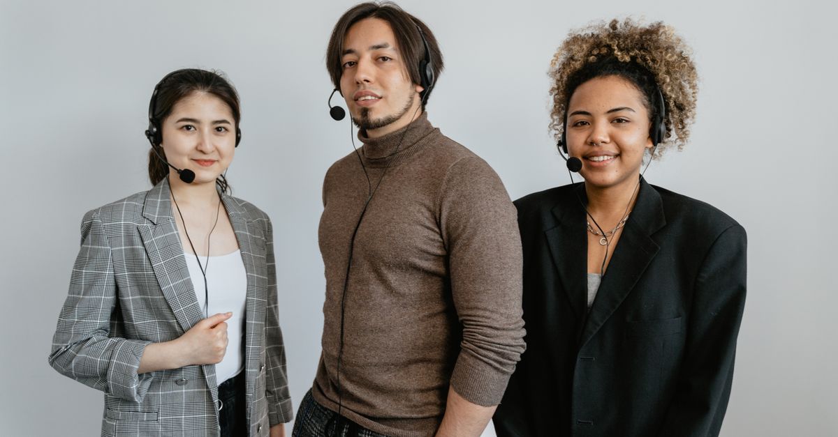 Three diverse customer support representatives wearing headsets and standing together.