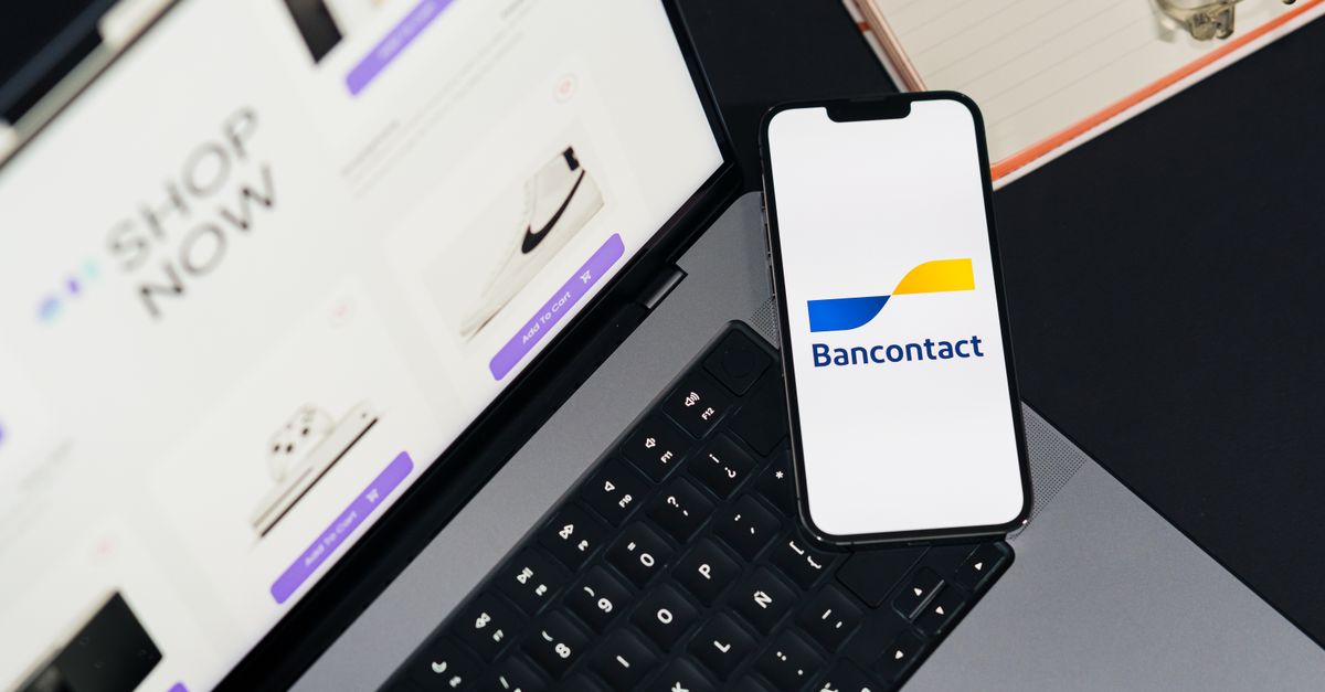 Smartphone displaying Bancontact app on laptop during online shopping.