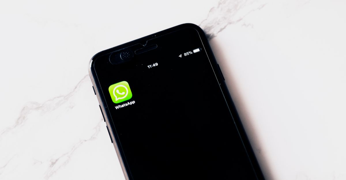 Close-up image of a smartphone displaying WhatsApp on a white table.