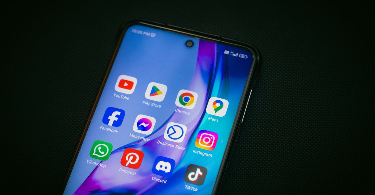 Close-up of a smartphone screen showing popular app icons like YouTube, Maps, and TikTok on a black background.